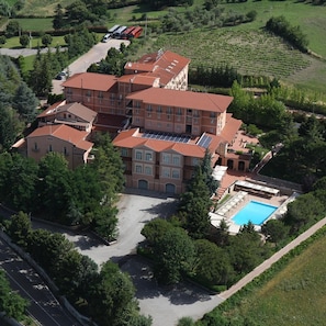 A multi-story hotel with a swimming pool, surrounded by greenery and vineyards. - Relais La Fattoria (Melfi)