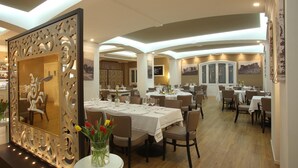 Un restaurante con varias mesas, sillas y un espejo decorativo con un arreglo floral.