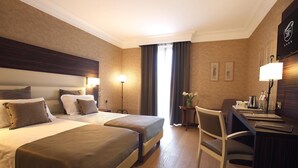 Una habitación de hotel con dos camas, un escritorio, una silla y una lámpara.