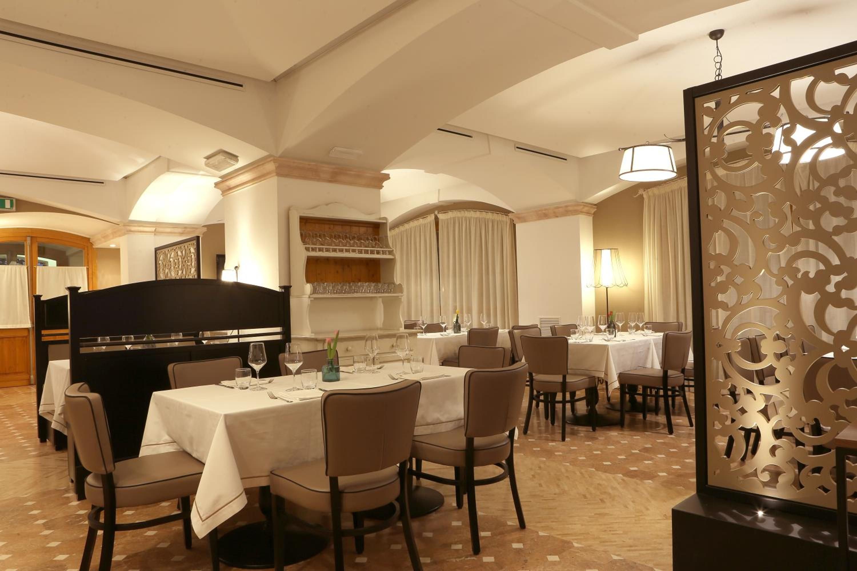 Un restaurante con mesas redondas, sillas y un separador decorativo.