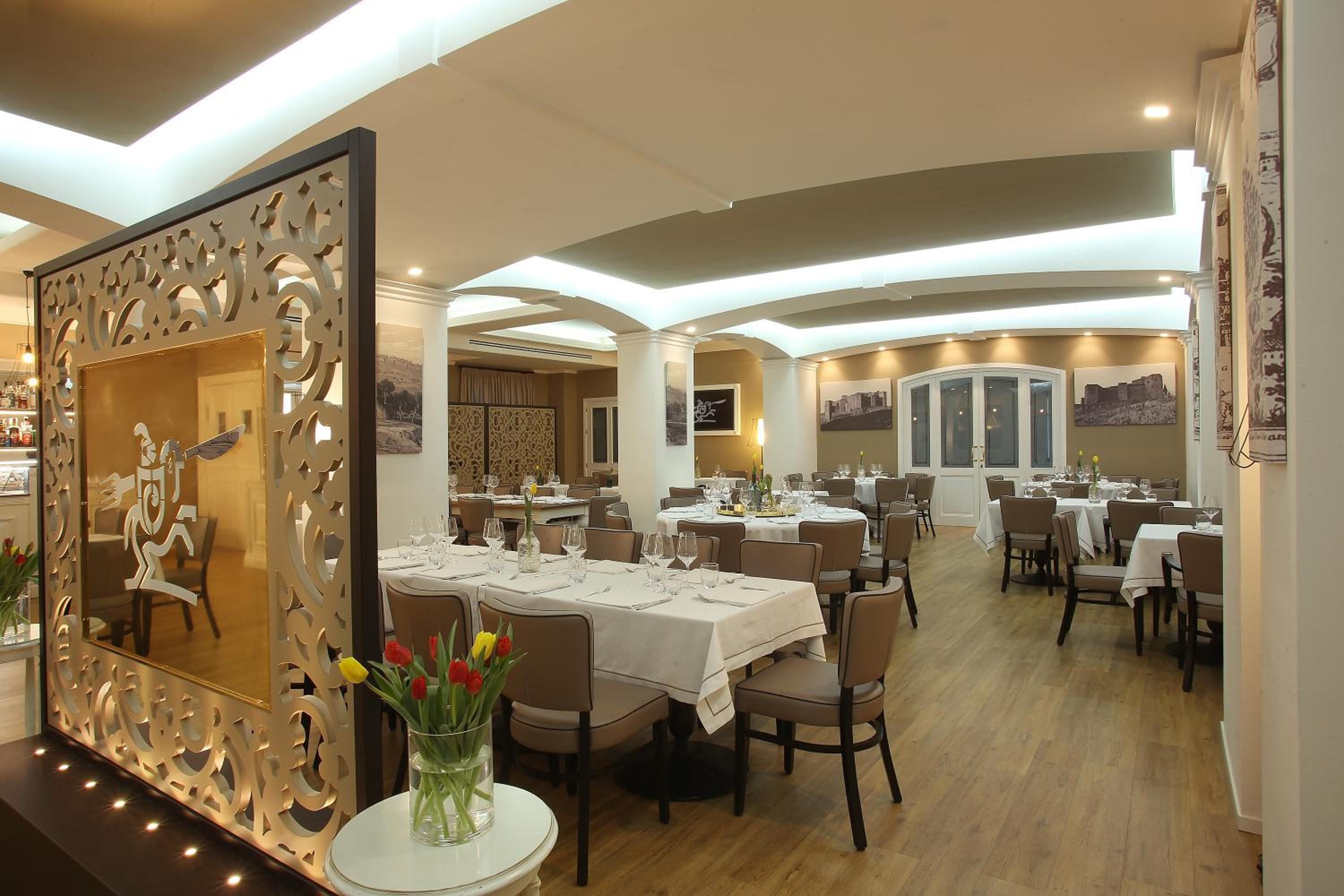 Ein Restaurant mit mehreren Tischen, Stühlen und einem dekorativen Spiegel mit Blumenarrangement.