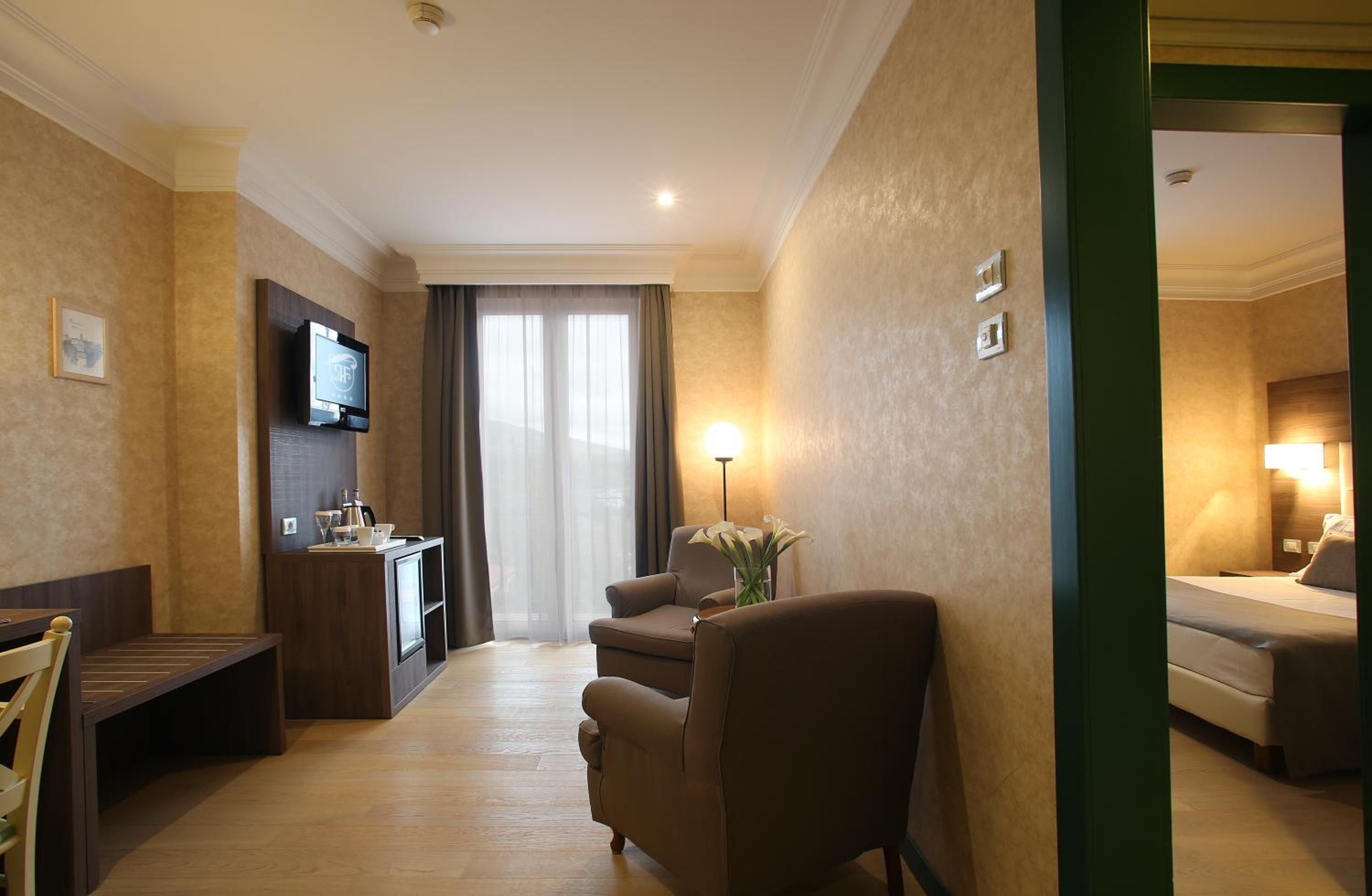 Una habitación de hotel con cama, escritorio, silla, televisor y lámpara.