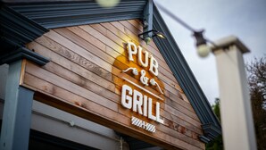 Een houten bordje met de tekst 'PUB & GRILL', wat aangeeft dat het een pub en grill is.