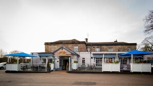 Een pub met een bord waarop "HARTWOOD PUB GRILL" staat en een overdekt terras.