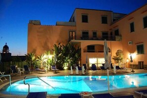 An outdoor swimming pool with lounge chairs and umbrellas, surrounded by a building with balconies and windows. - Hotel Terme Rosaleo (Casamicciola Terme)