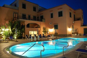 A swimming pool with lounge chairs and a building with balconies in the background. - Hotel Terme Rosaleo (Casamicciola Terme)