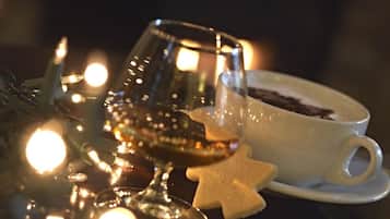 A glass of dark liquid, a white cup with a saucer, and a sugar cookie star on a reflective surface.