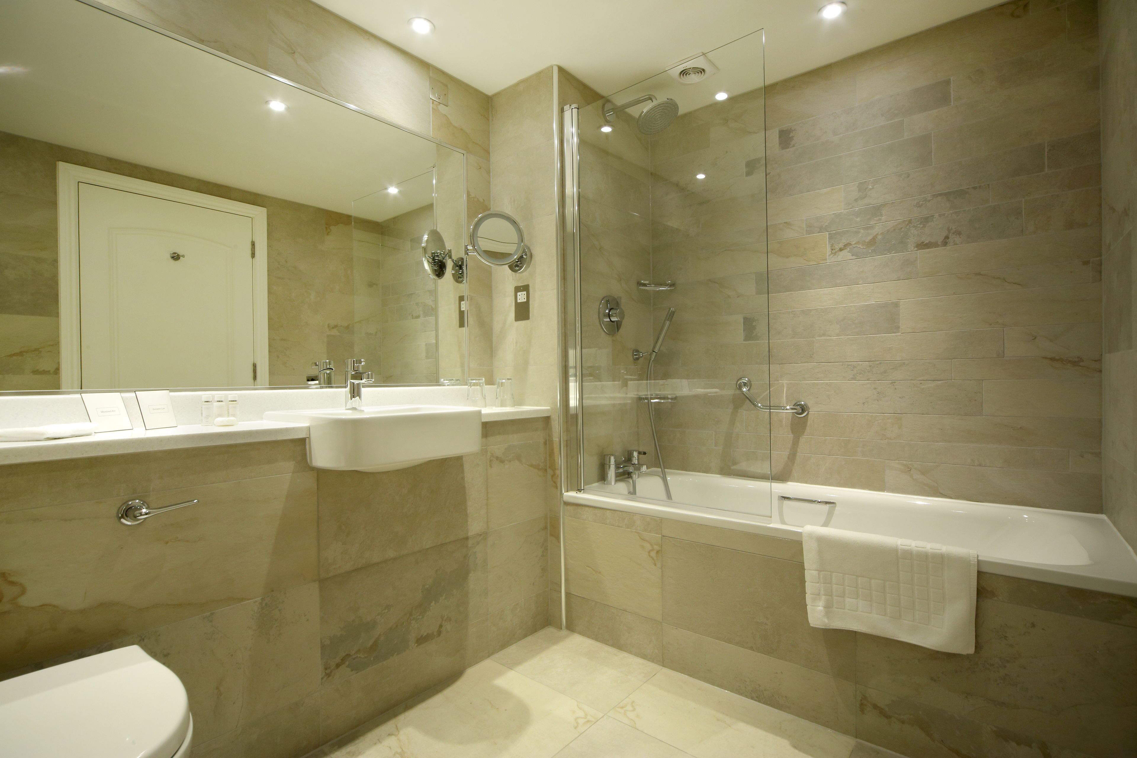 A modern bathroom with a glass-enclosed shower, a bathtub, and a toilet.