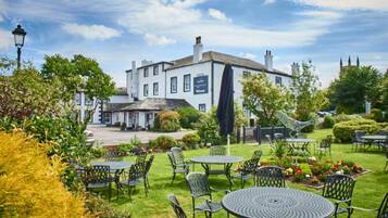 Guests can enjoy al fresco dining amidst lush greenery and vibrant flowers in this charming outdoor seating area.