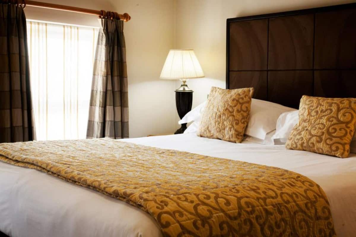 A hotel room with a large bed, a bedside lamp, and a headboard.