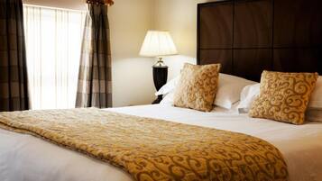 A hotel room with a large bed, a bedside lamp, and a headboard.