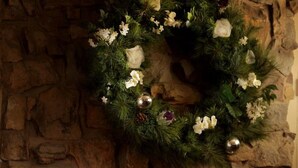 A fireplace with a stone wall backdrop, a wreath, and two glasses of champagne. - The Trout (Cockermouth)