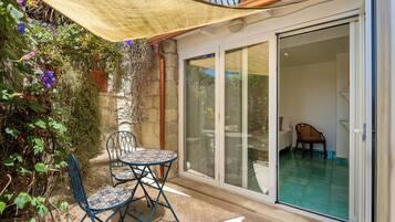 A patio with a table and chairs, a sliding glass door leading to a pool area, and a pergola providing shade.