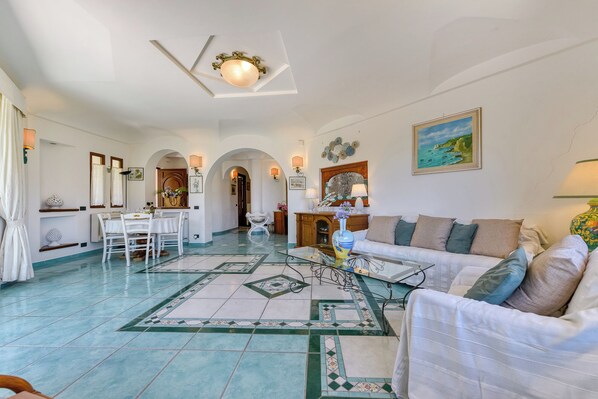A spacious living room with a dining area, a sofa set, and a decorative vase. - Hotel Villa Melodie - Adults Only (Forio)