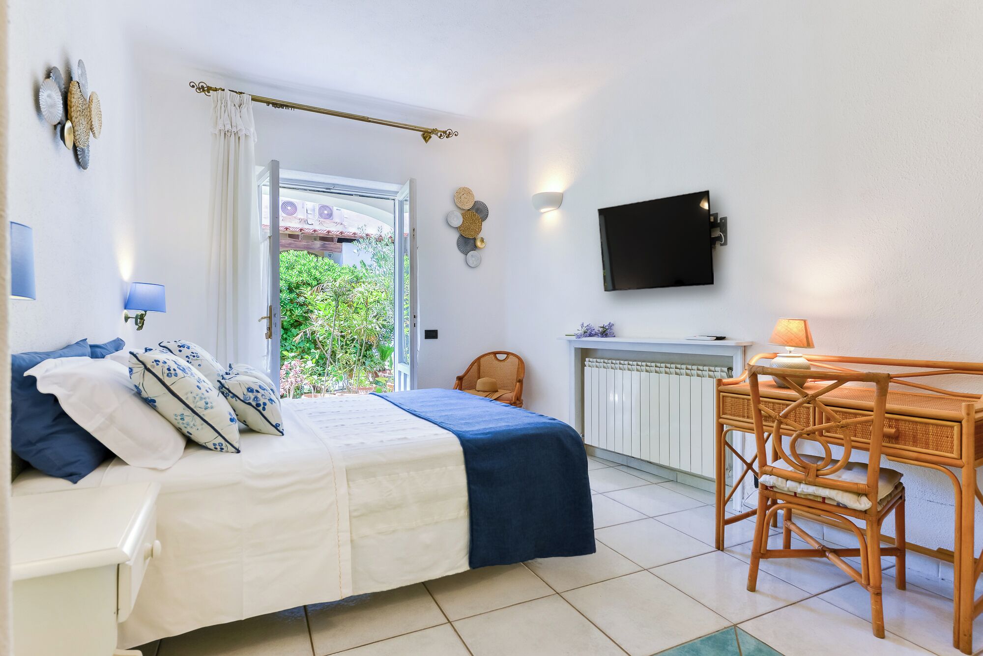 Une chambre à coucher comprenant un lit, un bureau, une chaise, un téléviseur et une fenêtre donnant sur un paysage verdoyant.