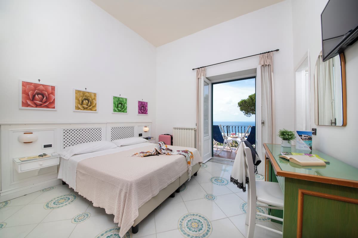 Un dormitorio con cama, escritorio y vista al mar.