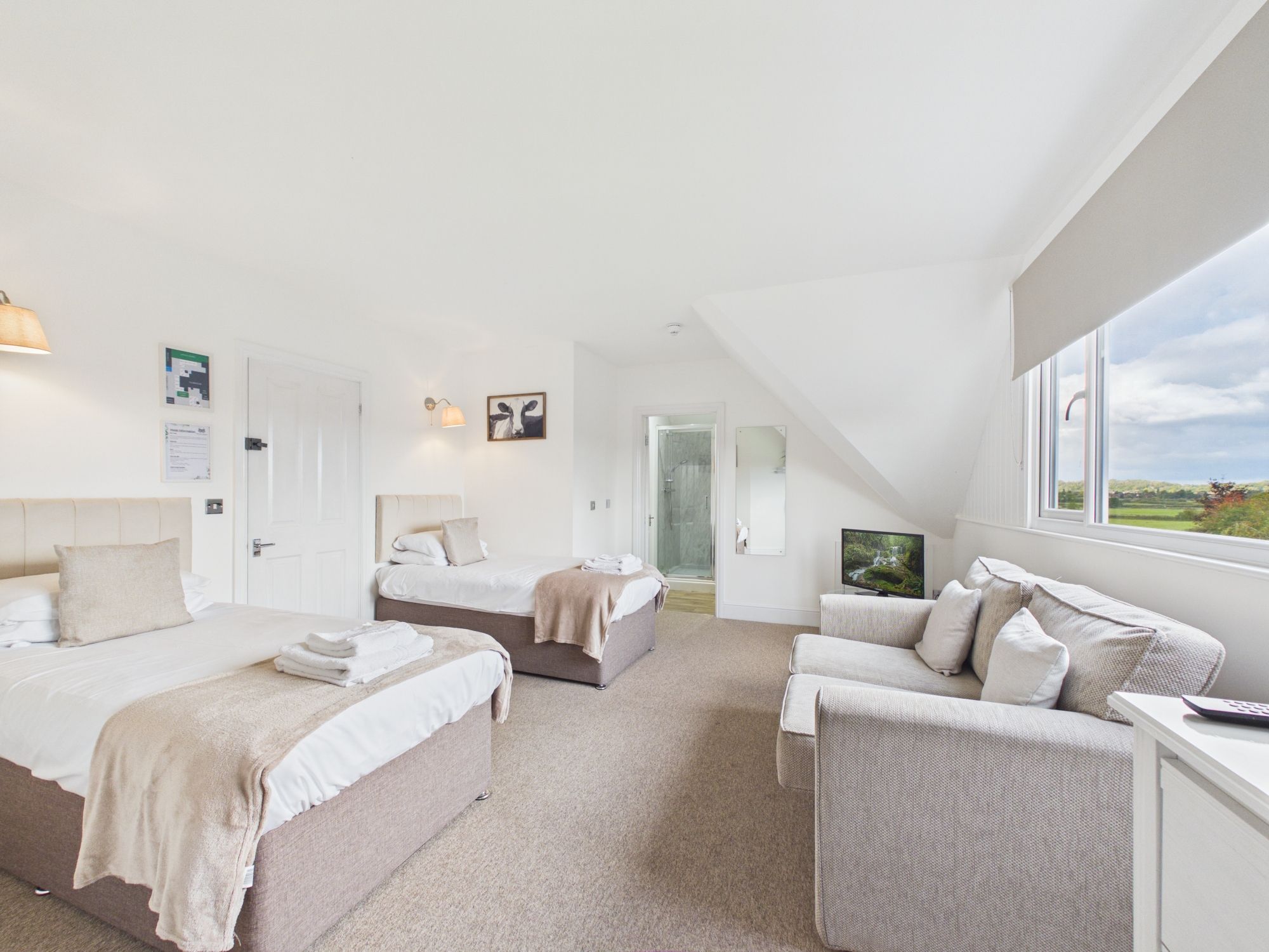 A spacious bedroom with two beds, a sofa, and a TV.
