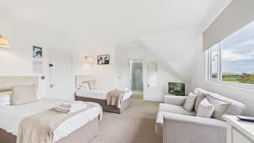 A spacious bedroom with two beds, a sofa, and a TV.