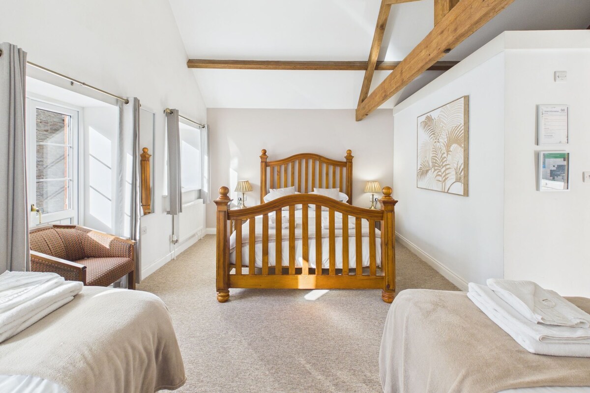 A bedroom with a wooden bed, two bedside tables, a chair, and a window with curtains.