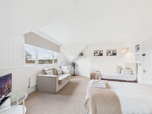 A modern bedroom with a sofa, a bed, a desk, and a view of the outdoors. - Mendip Spring Golf Club (Bristol)