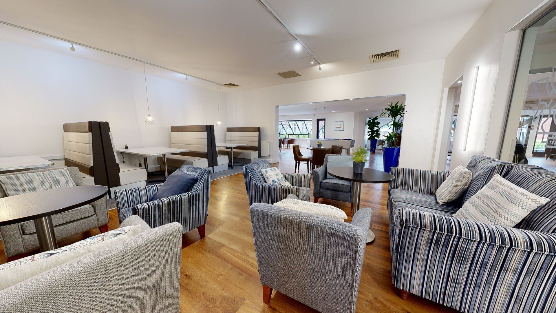 A modern lounge area with seating arrangements, a dining table, and a view of the outdoors.