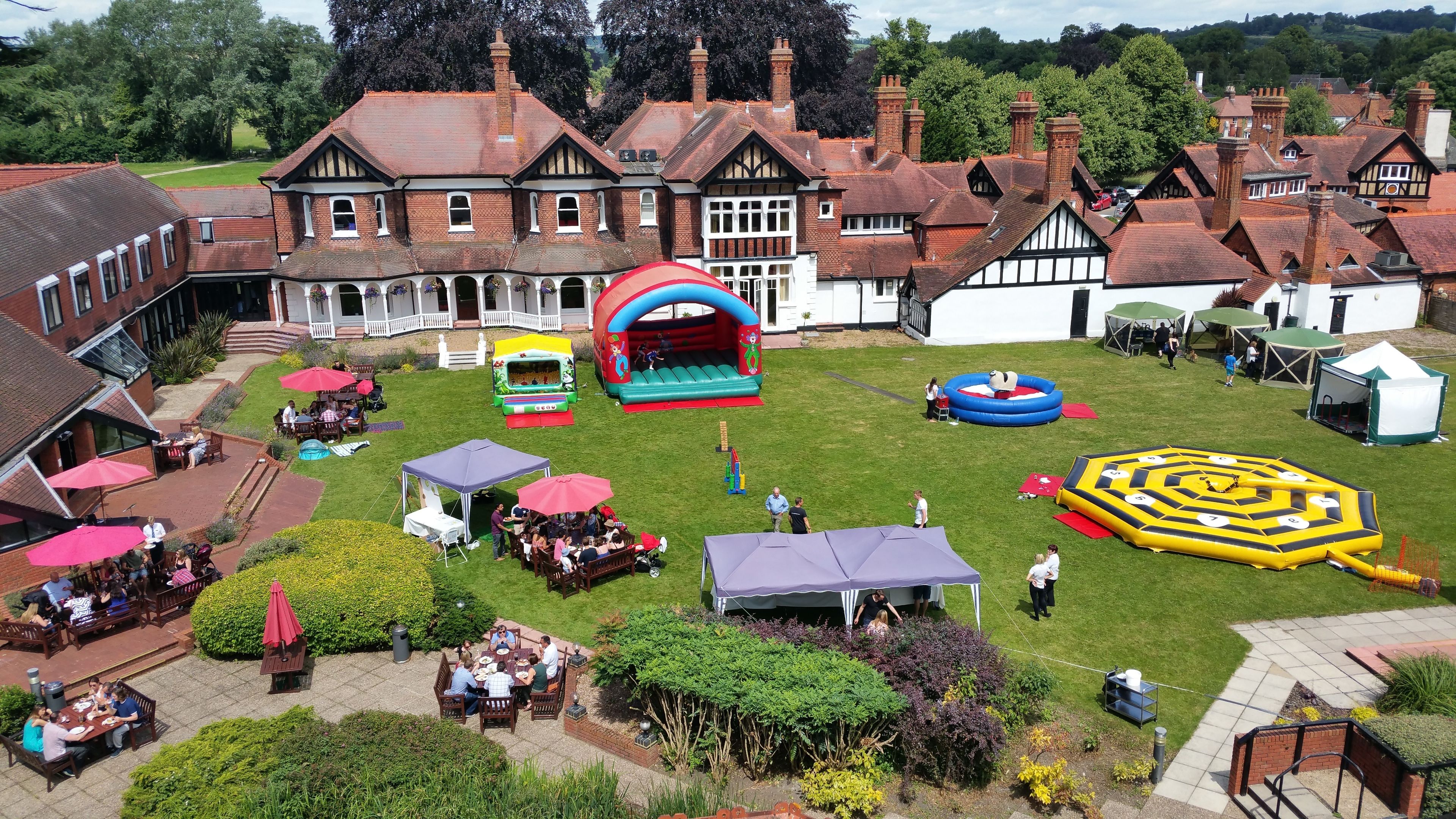 A courtyard with a large house, outdoor seating, and inflatable play structures.