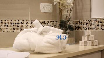 A bathroom with a white towel, a vase with white flowers, and a set of toiletries on the counter.