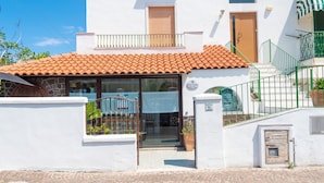 A white building with a tiled roof, a glass door entrance, and a small balcony. - Maison Twentyfive (Ischia)