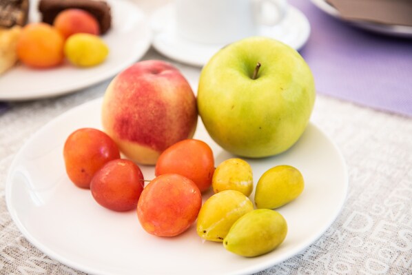 A plate with a green apple, red apple, and yellow and orange fruits on a tablecloth.