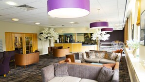 A hotel lobby with a reception desk, seating area, and bar. - Mitchell Hall (Bedford)