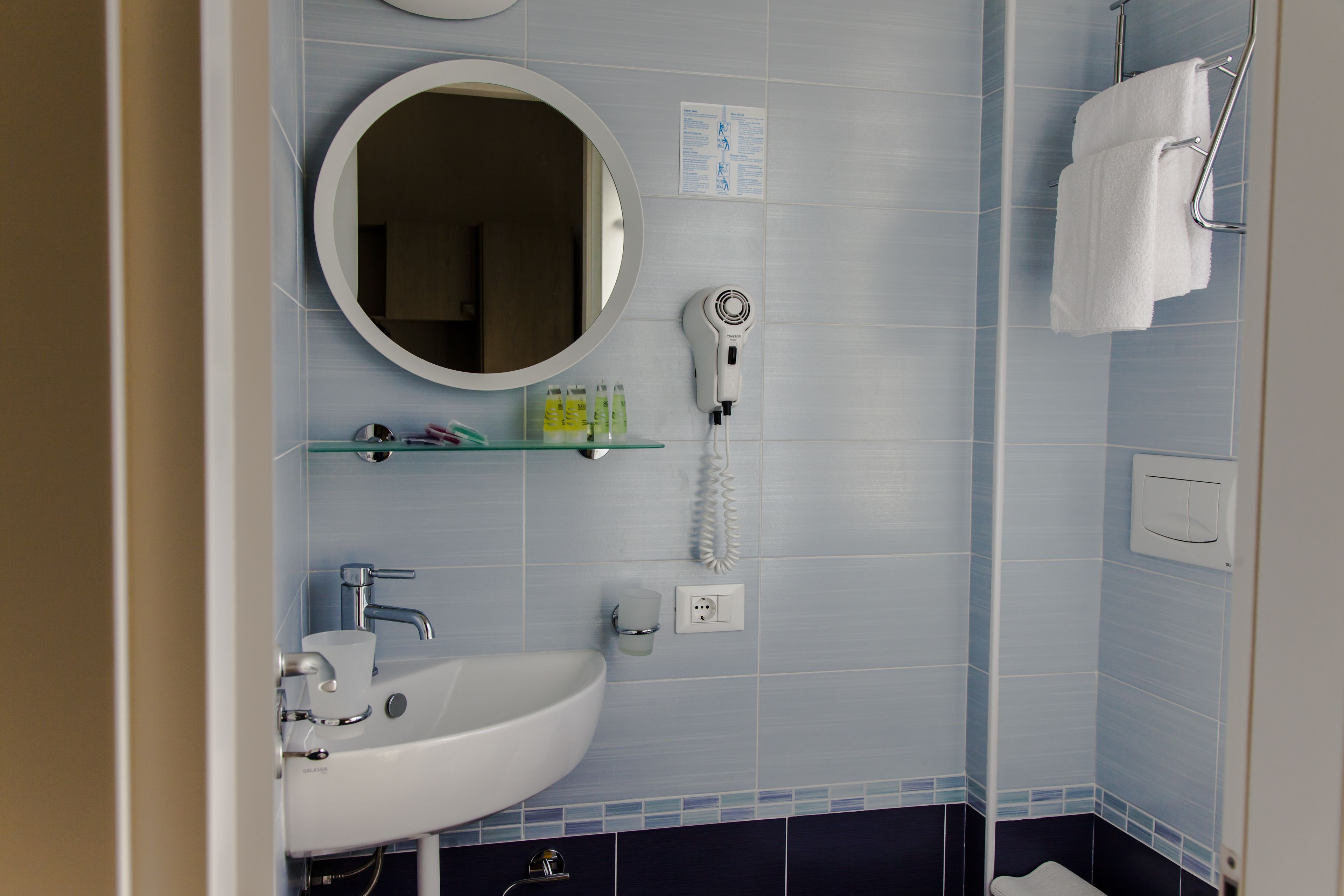 A bathroom with a sink, mirror, hairdryer, and towel rack.