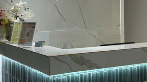 A reception desk with a marble finish, a flower arrangement, and a menu board. - Hotel Concorde (Bellaria-Igea Marina)