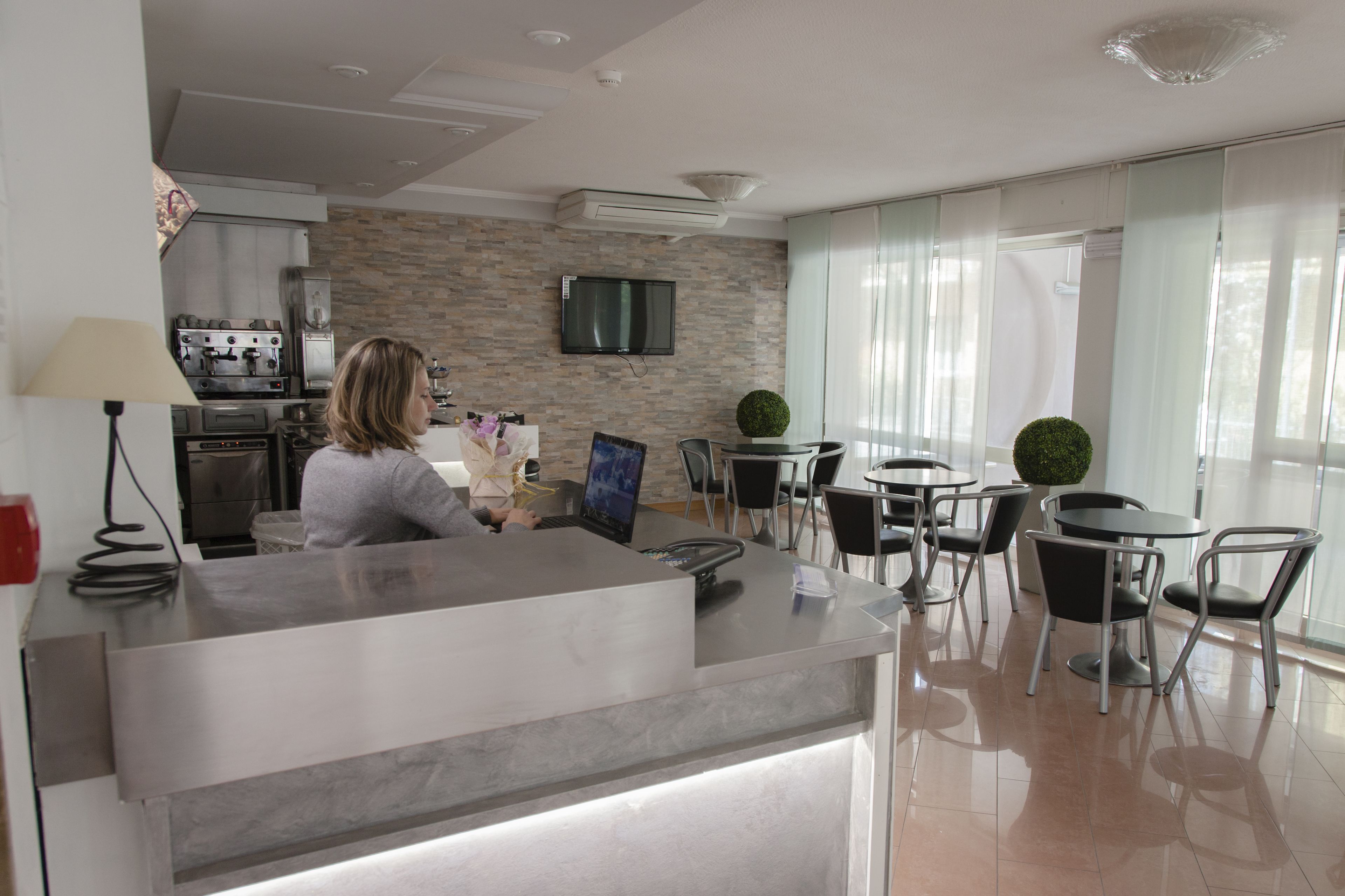 Un espace d’accueil moderne avec un comptoir, des sièges et une cuisine en arrière-plan.
