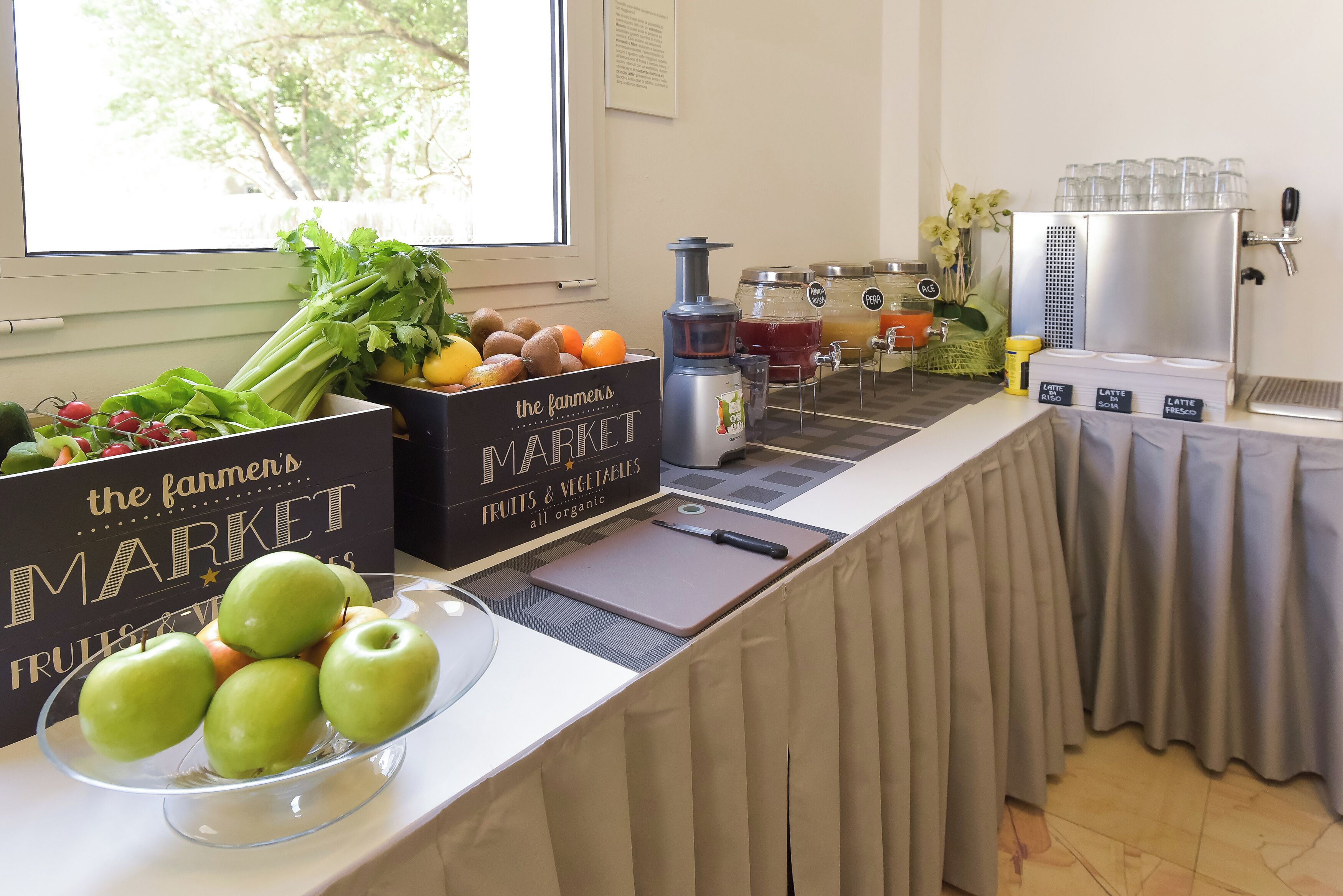 A breakfast bar with fresh fruits and vegetables, a juice station, and a coffee machine.