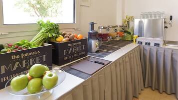 A breakfast bar with fresh fruits and vegetables, a juice station, and a coffee machine.