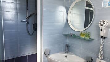 A bathroom with a shower, sink, mirror, and a hairdryer on a wall-mounted shelf.