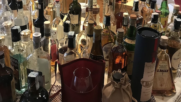 A table with various liquor bottles and a vase of roses. - La Torretta (Castel San Pietro Terme)