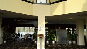 A hotel lobby with a Ripley's sign, seating area, potted plants, and a directional sign. - Padbrook Park (Cullompton)