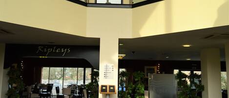Un vestíbulo de hotel con un cartel de Ripley's, zona de estar, plantas en macetas y una señal direccional.