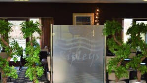 A reception area with a glass door, potted plants, and a framed picture on the wall. - Padbrook Park (Cullompton)