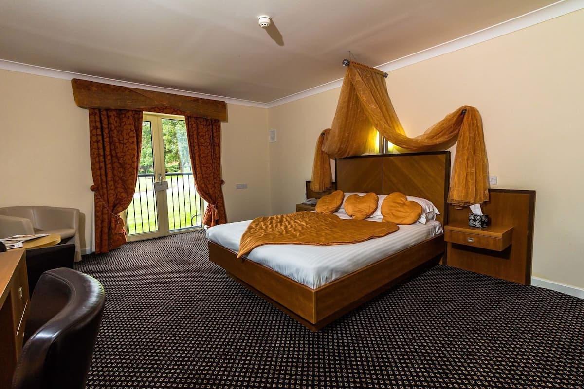 A hotel room with a bed, a desk, a chair, and a view of the outdoors.
