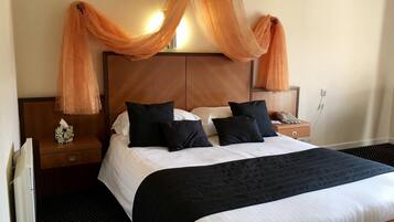 Quarto de hotel com uma cama grande, duas mesas de cabeceira e um dossel sobre a cama.