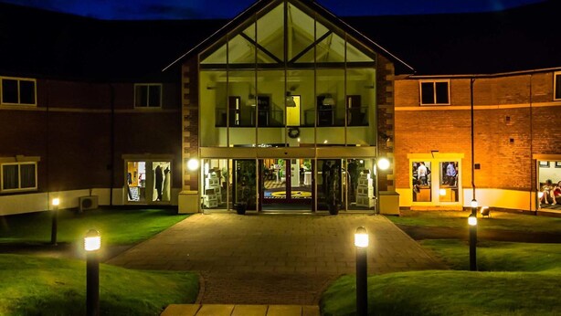 A two-story hotel with a glass facade, a central entrance, and a brick exterior. - Padbrook Park (Cullompton)