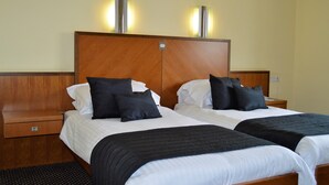 A hotel room with two beds, wooden headboards, and bedside tables. - Padbrook Park (Cullompton)
