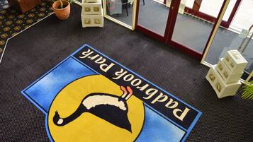 Zona de entrada con alfombra y un logotipo que muestra una ballena y el texto "Pacific Park".