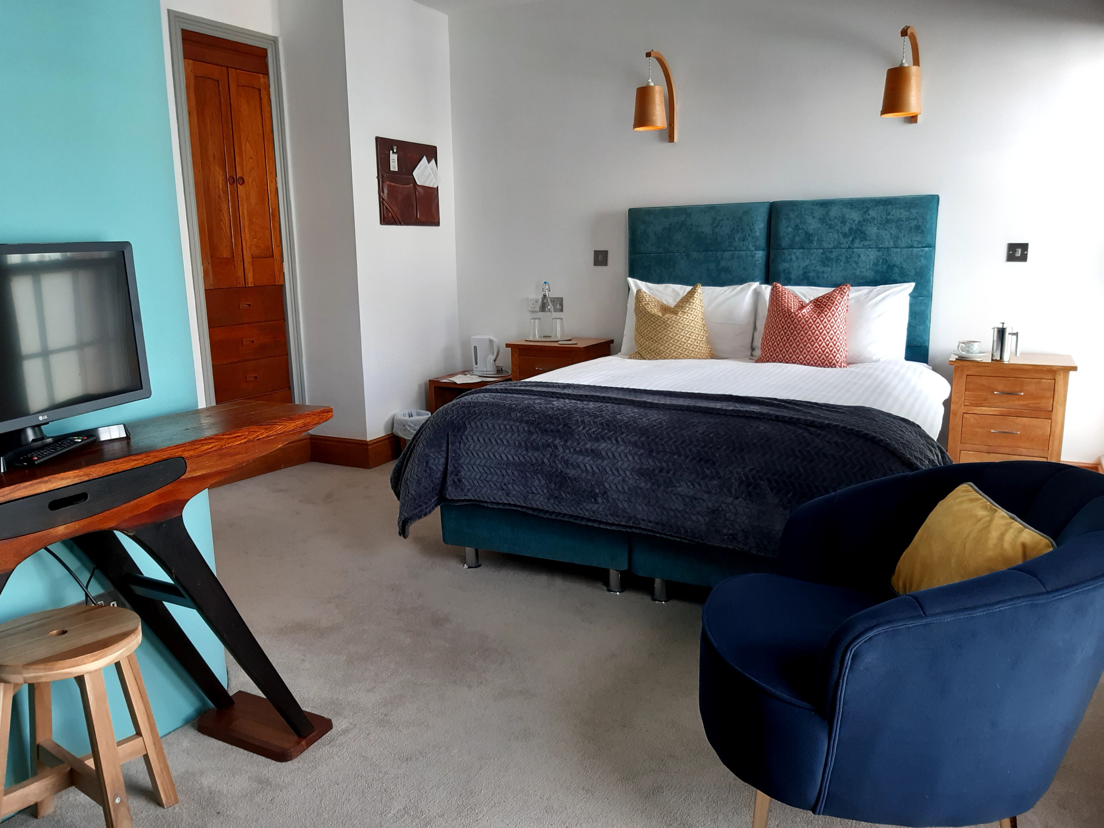 Un dormitorio moderno con cama, escritorio, silla y televisor.