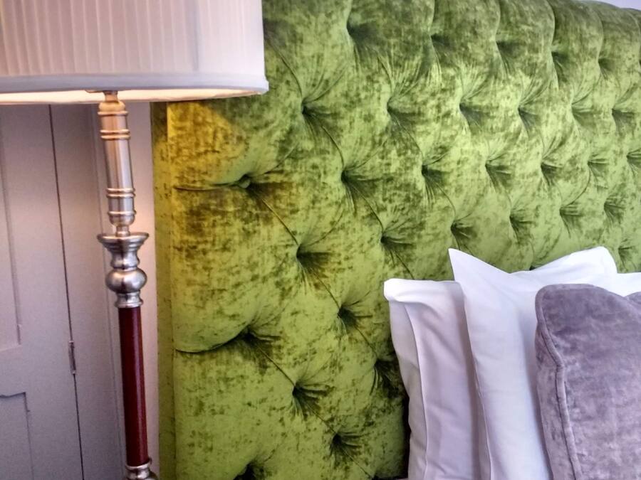 A bed with a tufted headboard, a bedside lamp, and pillows.