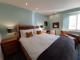 Habitación de hotel con una cama grande, un escritorio, una silla y una ventana con persianas.