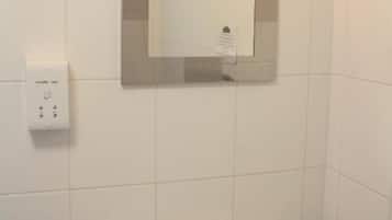 A bathroom with a white sink, a mirror, and a light fixture above the mirror.