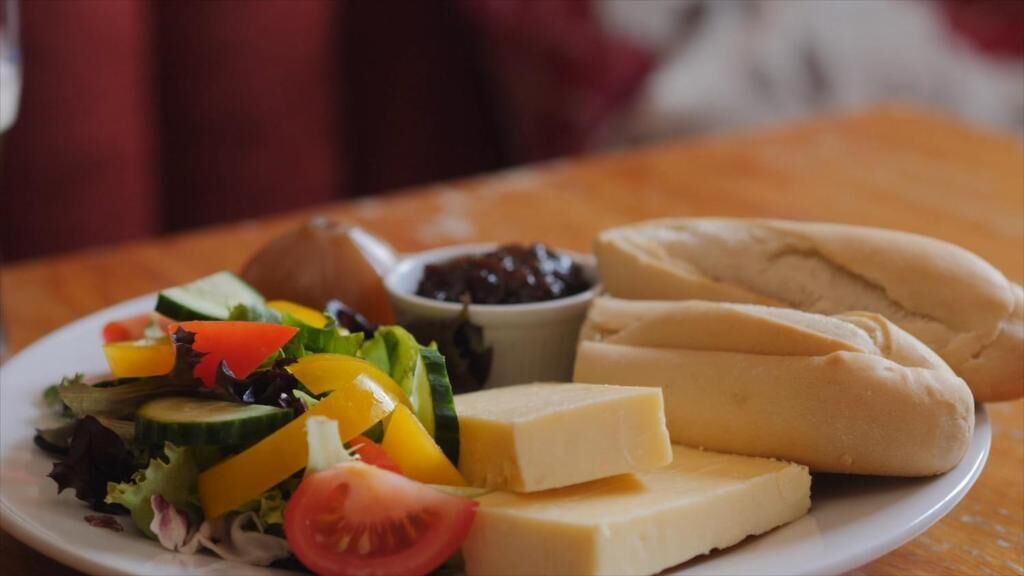 A plate with a salad, cheese, and a sandwich.